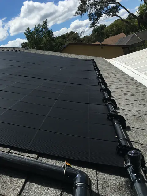 Technician servicing solar pool heating collectors on a Florida roof